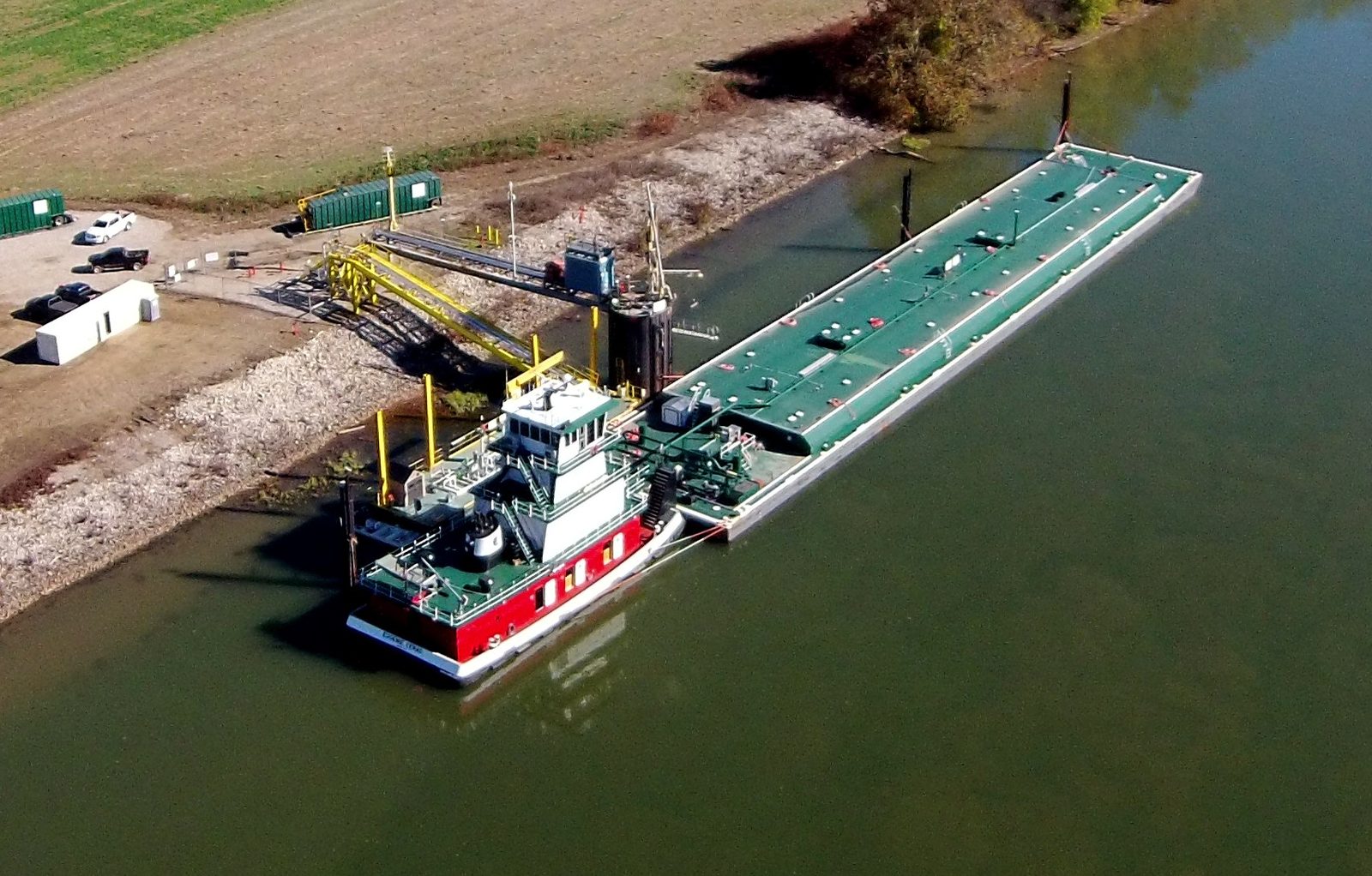 A towboat and barge at a river-dock loading facility
