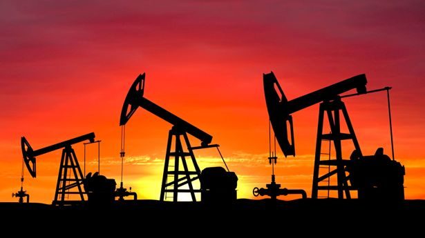 Pumpjacks silhouetted against a sunset sky in an oil field